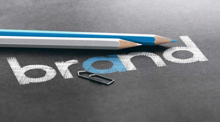 Two pencils and a paperclip rest on a black surface near the word 