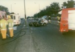 A completely wrecked car that is being attended to by firemen in June 1989 that Clive, Jess and their friends were in