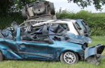 An image of a car wreck, they are others in the background Collection of Wrecked Cars in a Countryside Field.