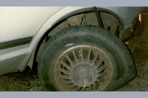 A car with a damaged tyre and a visible gash on the tyre’s sidewall.
