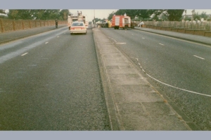 A police car and a fire engine are parked on a divided road with emergency tape across the median.