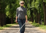 A blind woman wearing sunglasses with a white stick