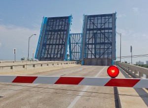 A double drawbridge opened up with the barrier gate down and the red  light lit