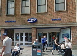 Outside photo Boots Stores Chichester, people are outside including a woman being pushed in a wheelchair