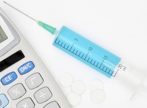 Calculator and a syringe with blue liquid inside