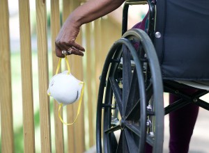 Close-up of a wheelchair user holding a mask in their left hand