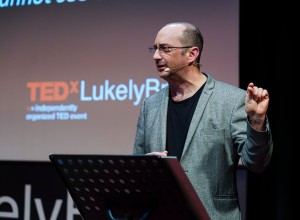 Clive giving his Ted Talk. Behind him, a screen says \TEDx Lukely Brook\