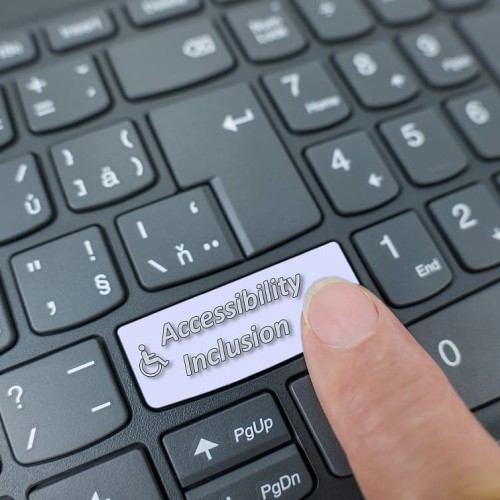Accessibility and inclusion key on a gray keyboard. Finger pressing key 