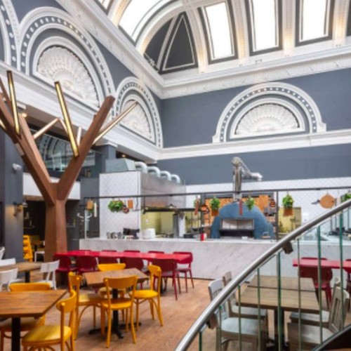 A cafe inside an old hotel. There is a curving staircase in the foreground.