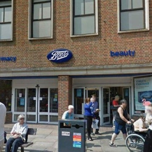 Outside photo Boots Stores Chichester, people are outside including a woman being pushed in a wheelchair