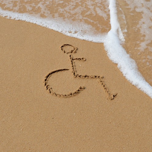 A wheelchair symbol drawn in the sand, the tide is coming in