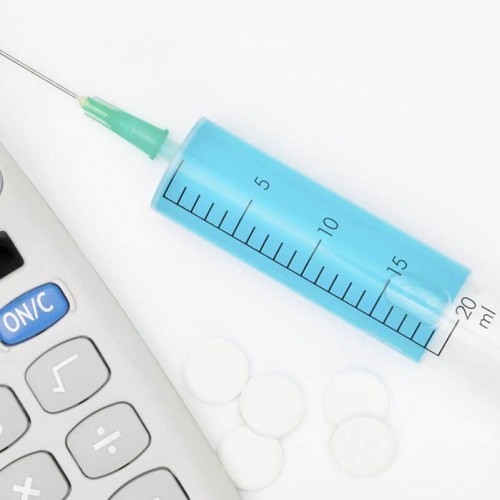Calculator and a syringe with blue liquid inside