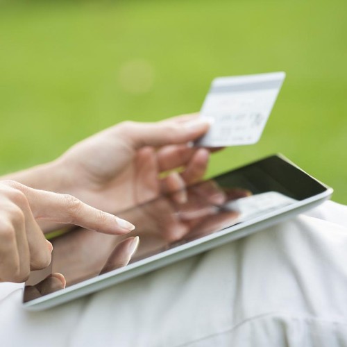 Close-up of a woman with a tablet, holding a credit card