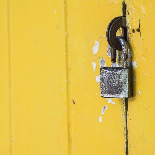 rusty padlock on vintage yellow door