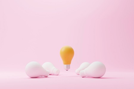 A lit lightbulb, floating in the air. 4 unlit lightbulbs lie on the floor below it