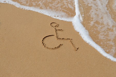 A wheelchair symbol drawn in the sand, the tide is coming in