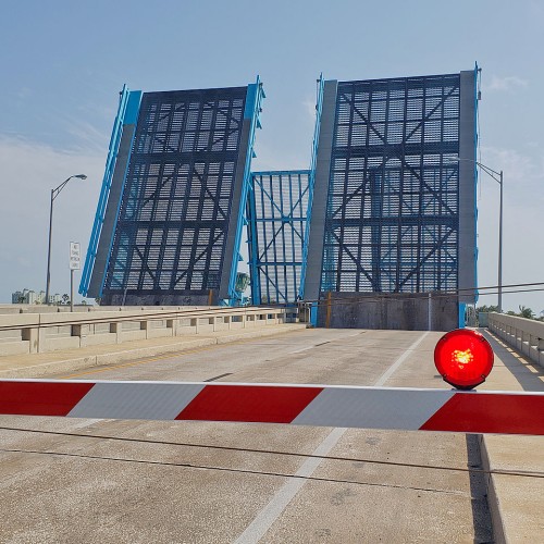 A double drawbridge opened up with the barrier gate down and the red  light lit