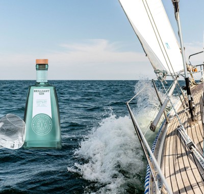 Brilliant GIn bottle superimposed over a dramatic image of a yacht riding the waves