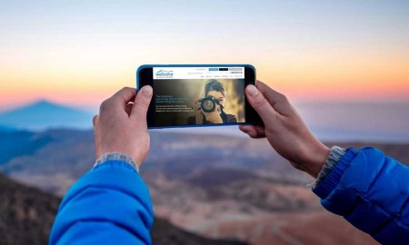 Close-up looking at Run Your Own Website on a smartphone with mountains in the background