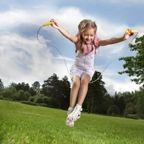 a young girl is playing with a skipping rope