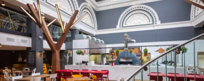 A cafe inside an old hotel. There is a curving staircase in the foreground.