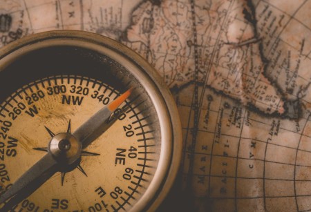 an old compass on top of an old map of the world