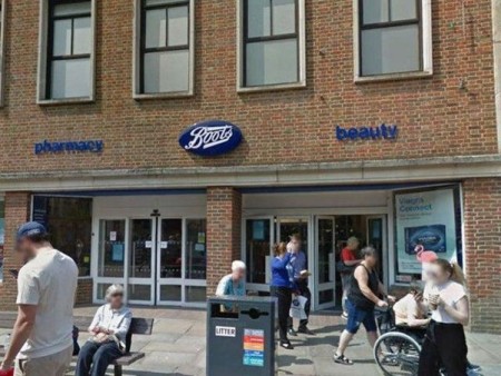 Outside photo Boots Stores Chichester, people are outside including a woman being pushed in a wheelchair