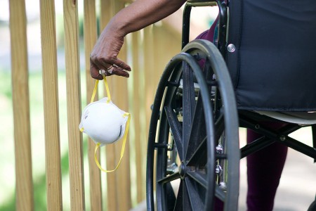 Close-up of a wheelchair user holding a mask in their left hand