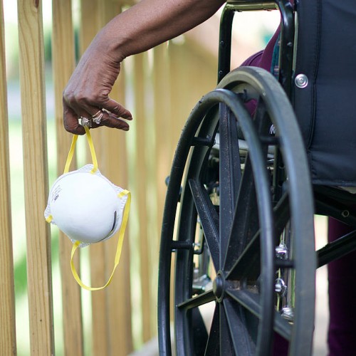 Close-up of a wheelchair user holding a mask in their left hand