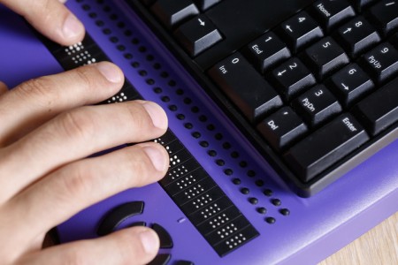 Blind person using computer with braille computer display and a computer keyboard