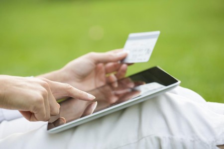 Close-up of a woman with a tablet, holding a credit card