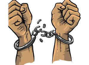 Two clenched fists, pointing upwards, in handcuffs that have been broken apart