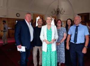 Littlehampton Town Council Millennium Chamber interior. John Donoghue, Clive Loseby, Alison Griffiths MP, Tina Shaw-Morton, Freya Reynolds, and Dominic Reynolds stand smiling in a group photo.