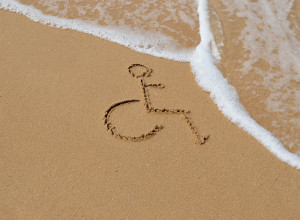 A wheelchair symbol drawn in the sand, the tide is coming in