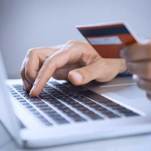 Person at a laptop holding a credit card