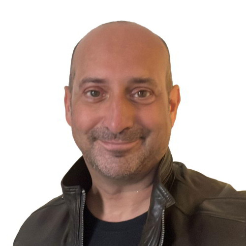 Clive has brown eyes, no hair, has shaped stubble and is smiling