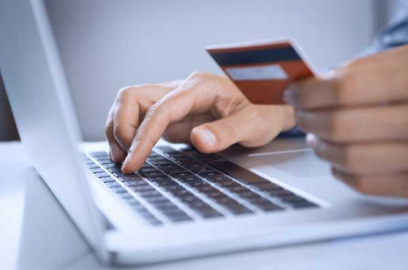 Person at a laptop holding a credit card