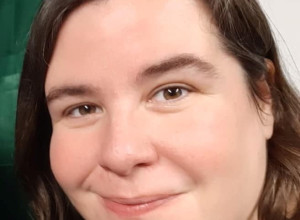 Iona has brown hair and brown eyes. She is smiling